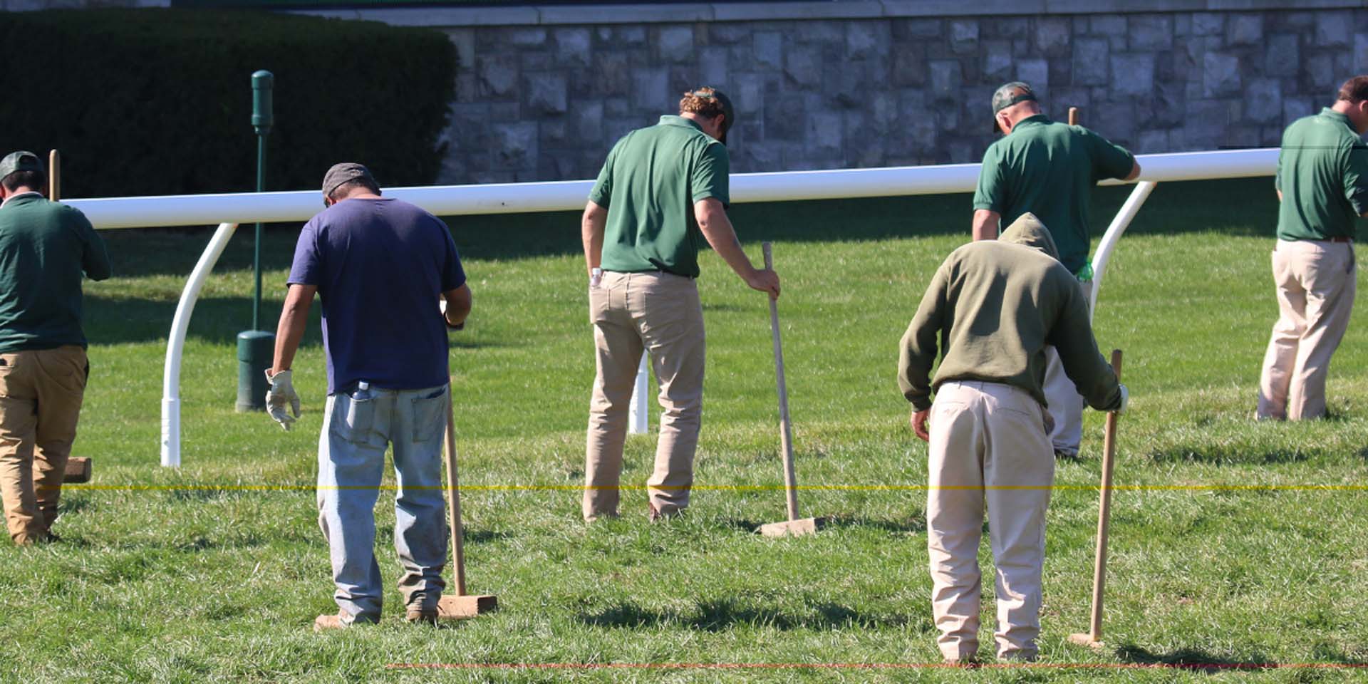 An action shot of Keenrush team members tamping down turf divots.